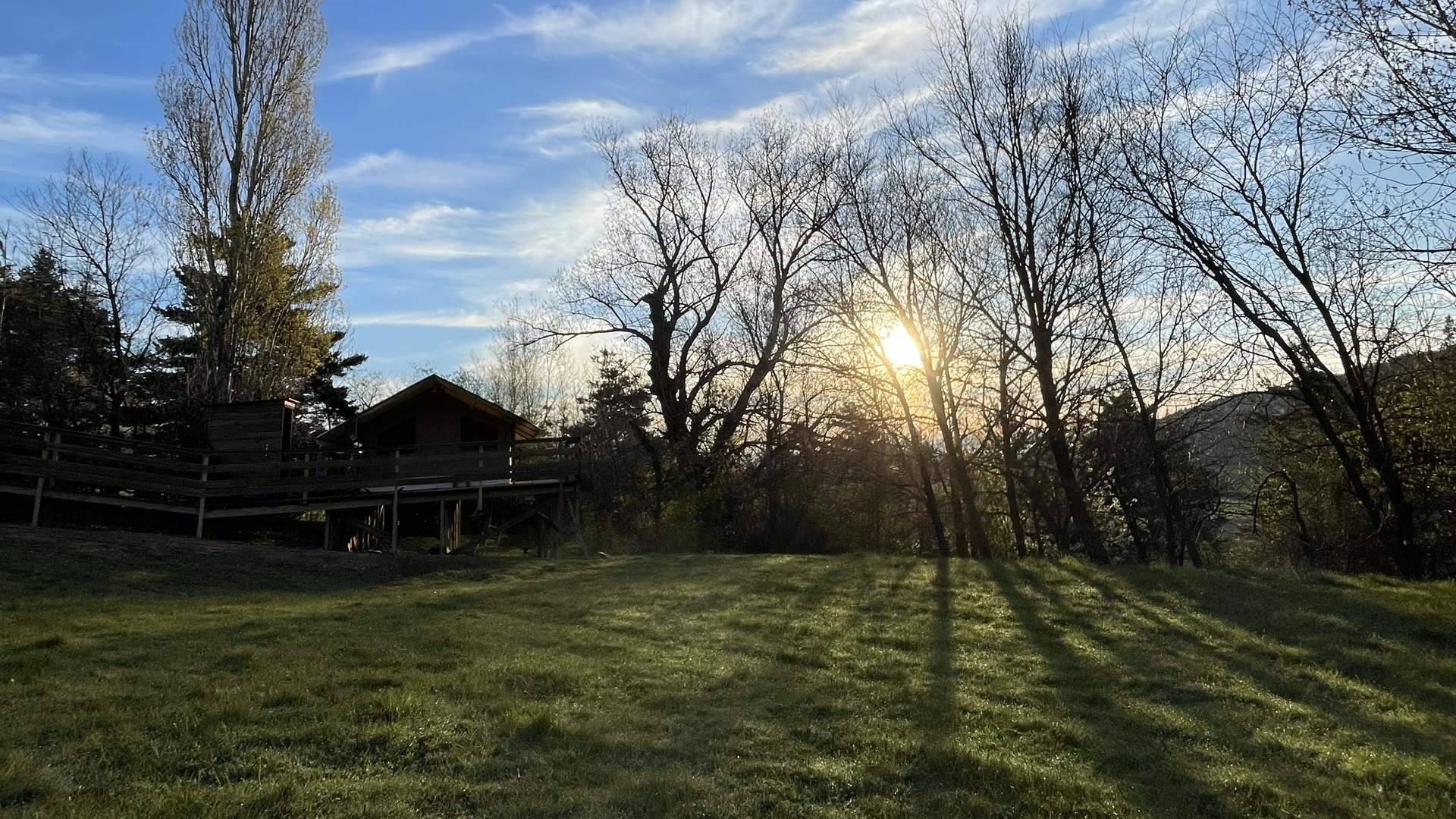 Le soleil se lève derrière les arbres au bout du pré du Domaine Solio, en Ardèche