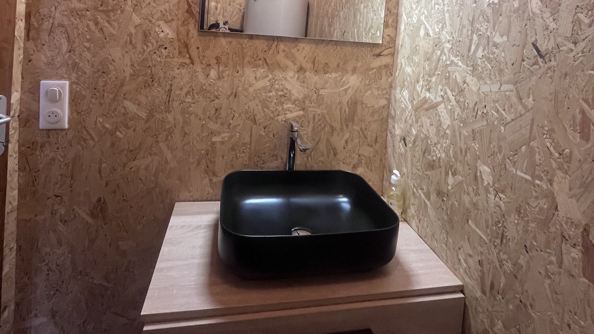 Vasque noire et miroir dans la salle d'eau privative en bois de la tente safari
