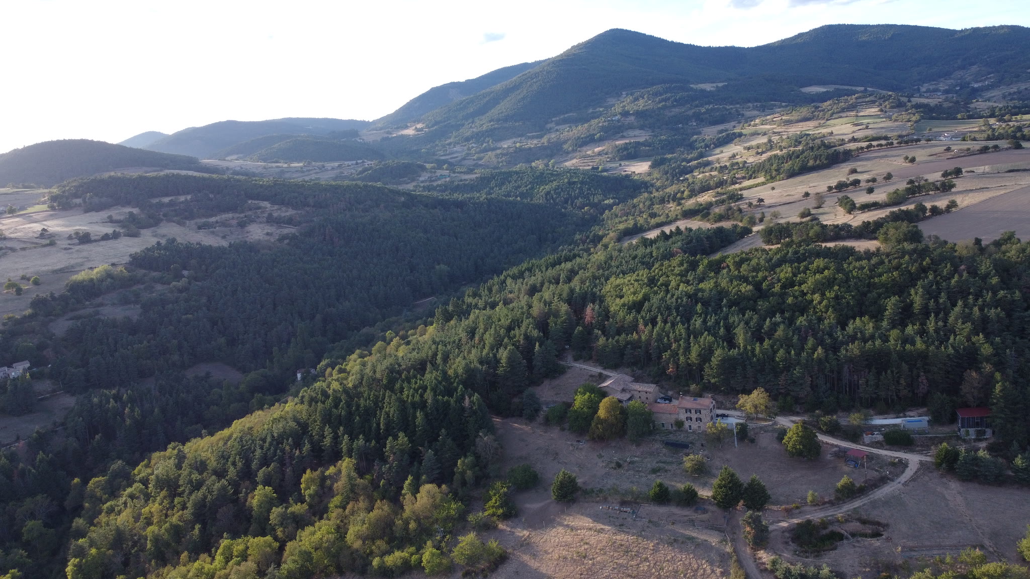 Domaine Solio from the air, tucked into the pines with its meadows and paths, the hills of the Ardèche verte to the horizon