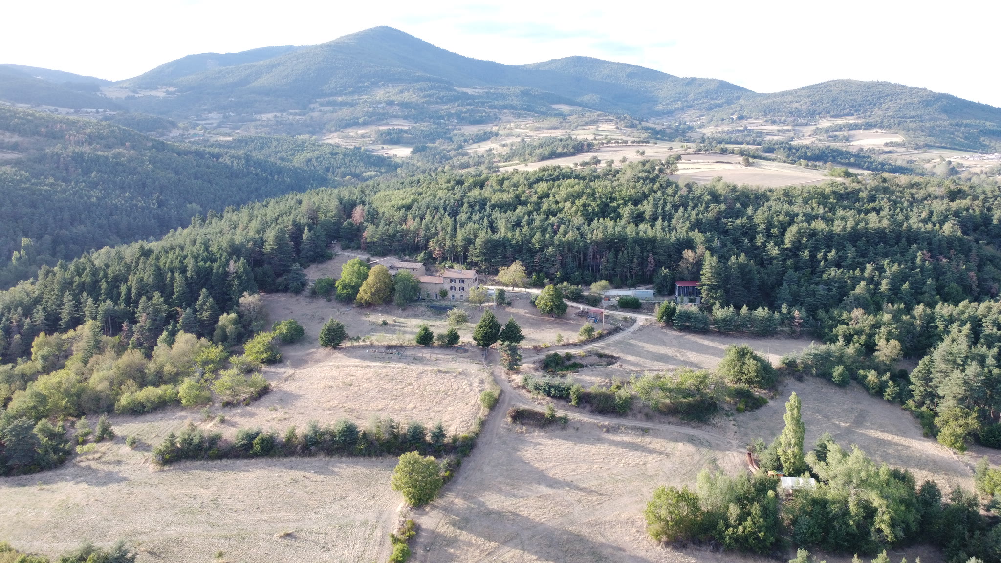 Le Domaine Solio vu du ciel : les prairies, la forêt et la bâtisse, la vallée d'Ardèche à l'horizon