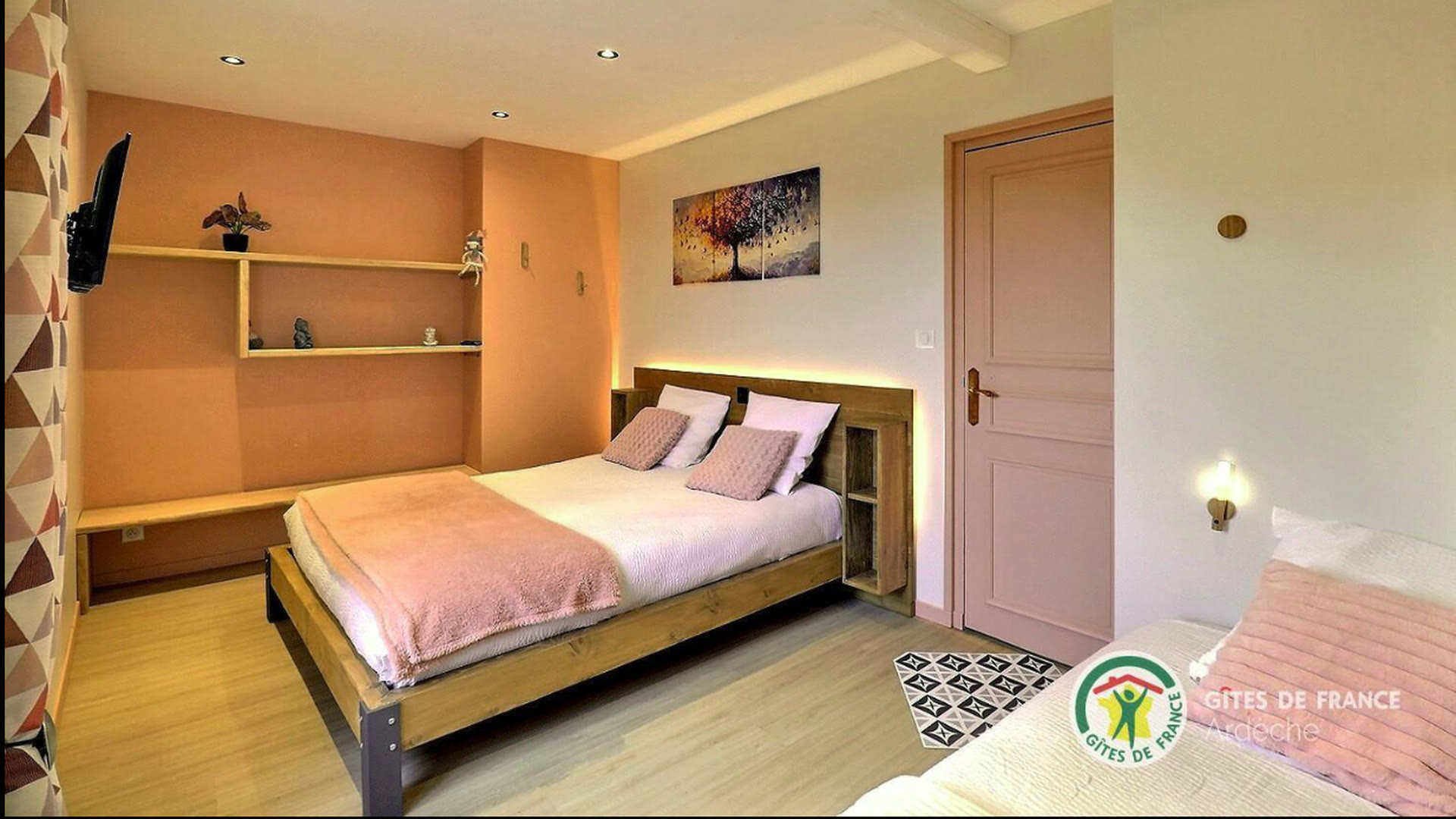 Chambre du gîte avec un lit double, murs ocre et étagères en bois