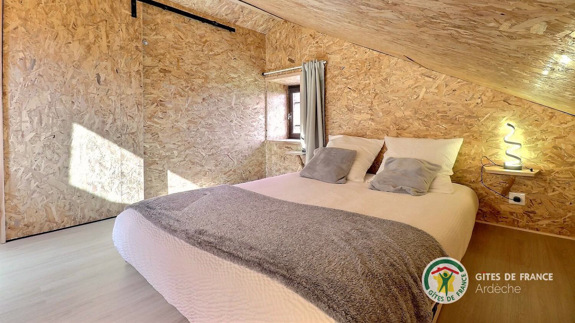 Chambre mansardée du gîte, lit double sous les pentes de bois clair
