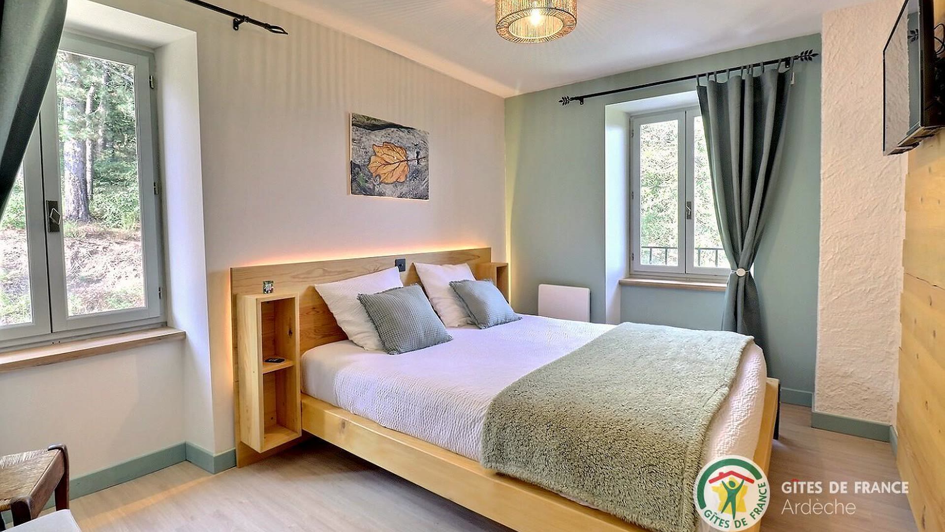 Chambre du gîte avec un lit double face à une fenêtre ouverte sur la forêt