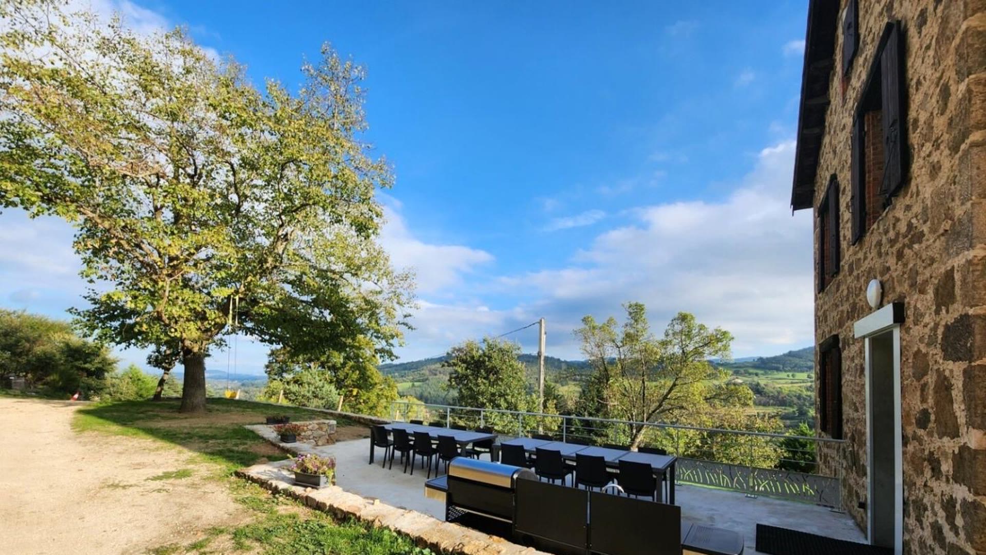 Grande table extérieure sous le tilleul devant le gîte en pierre du Domaine Solio