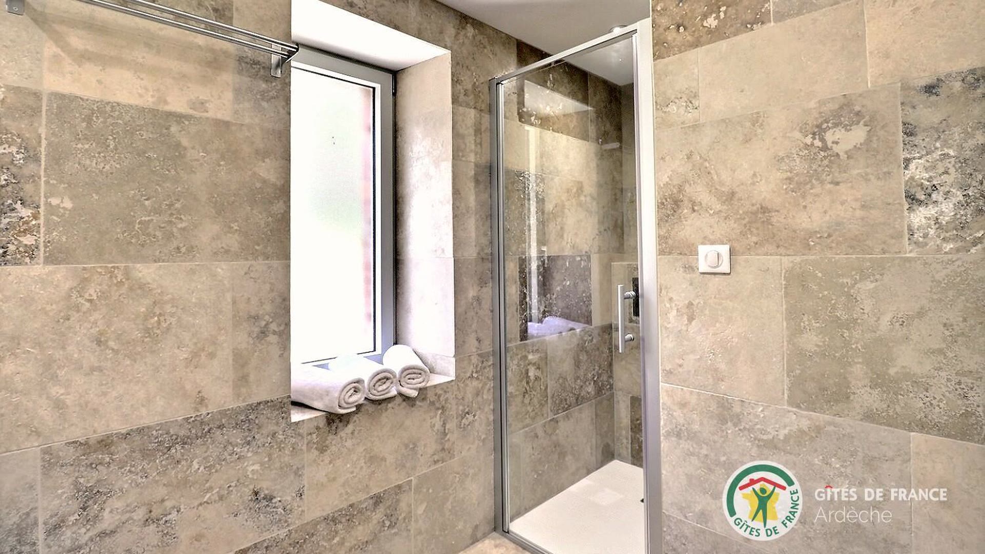 Douche à l’italienne du gîte, paroi vitrée et carrelage travertin