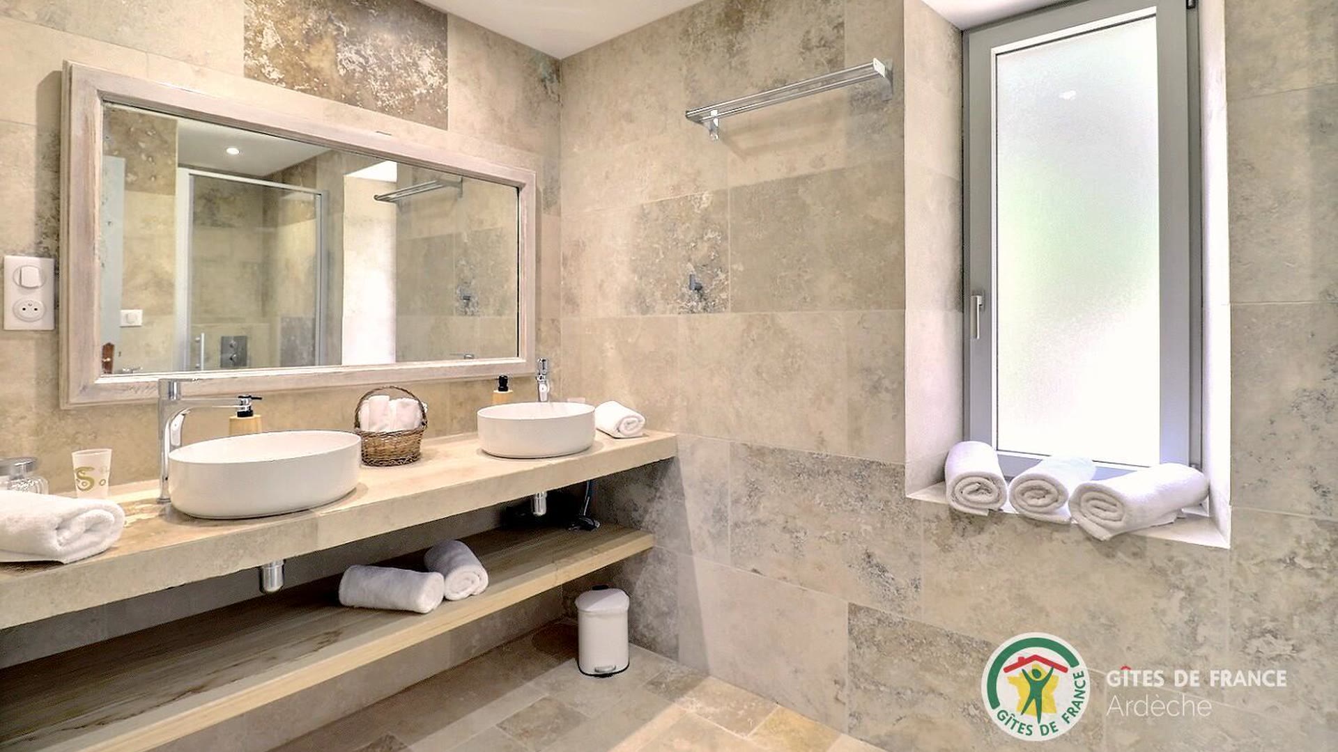 Salle d’eau du gîte avec double vasque, grand miroir et carrelage clair