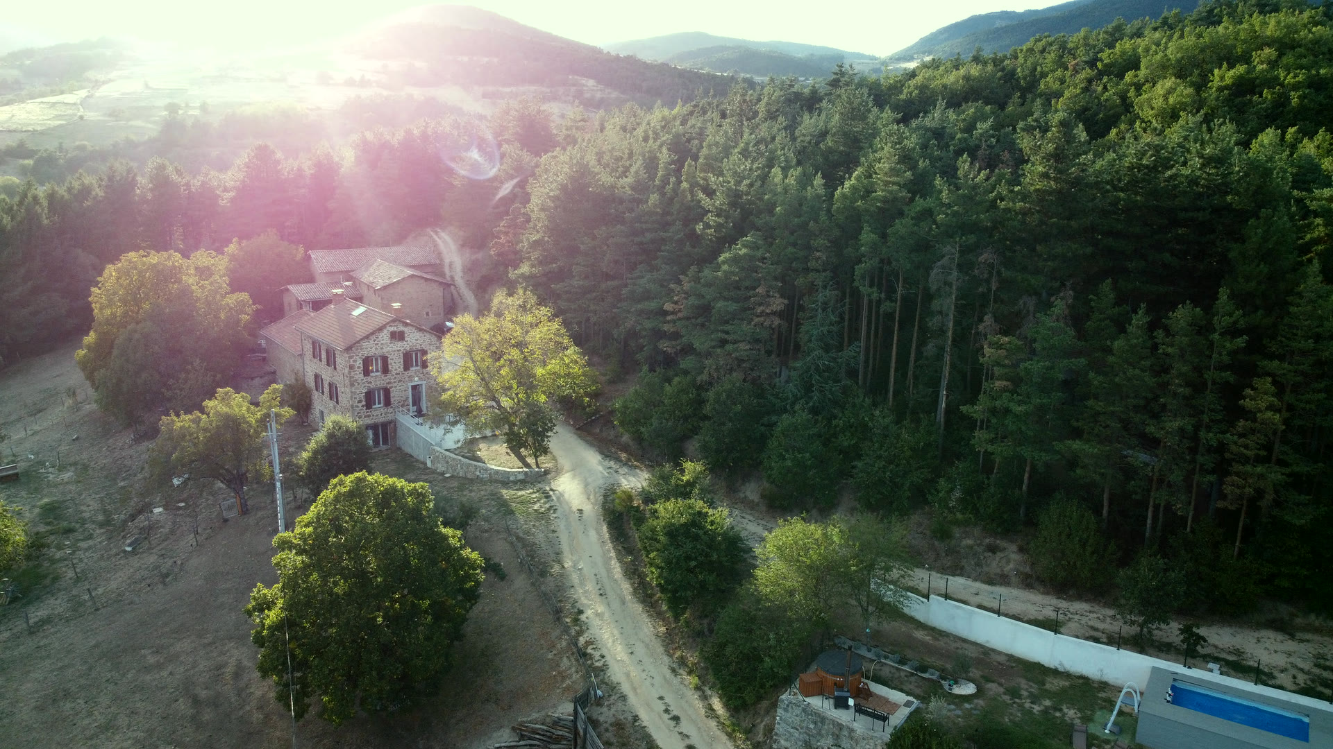 Vue aérienne du gîte du Domaine Solio au soleil couchant, la pinède et les collines de l'Ardèche verte derrière