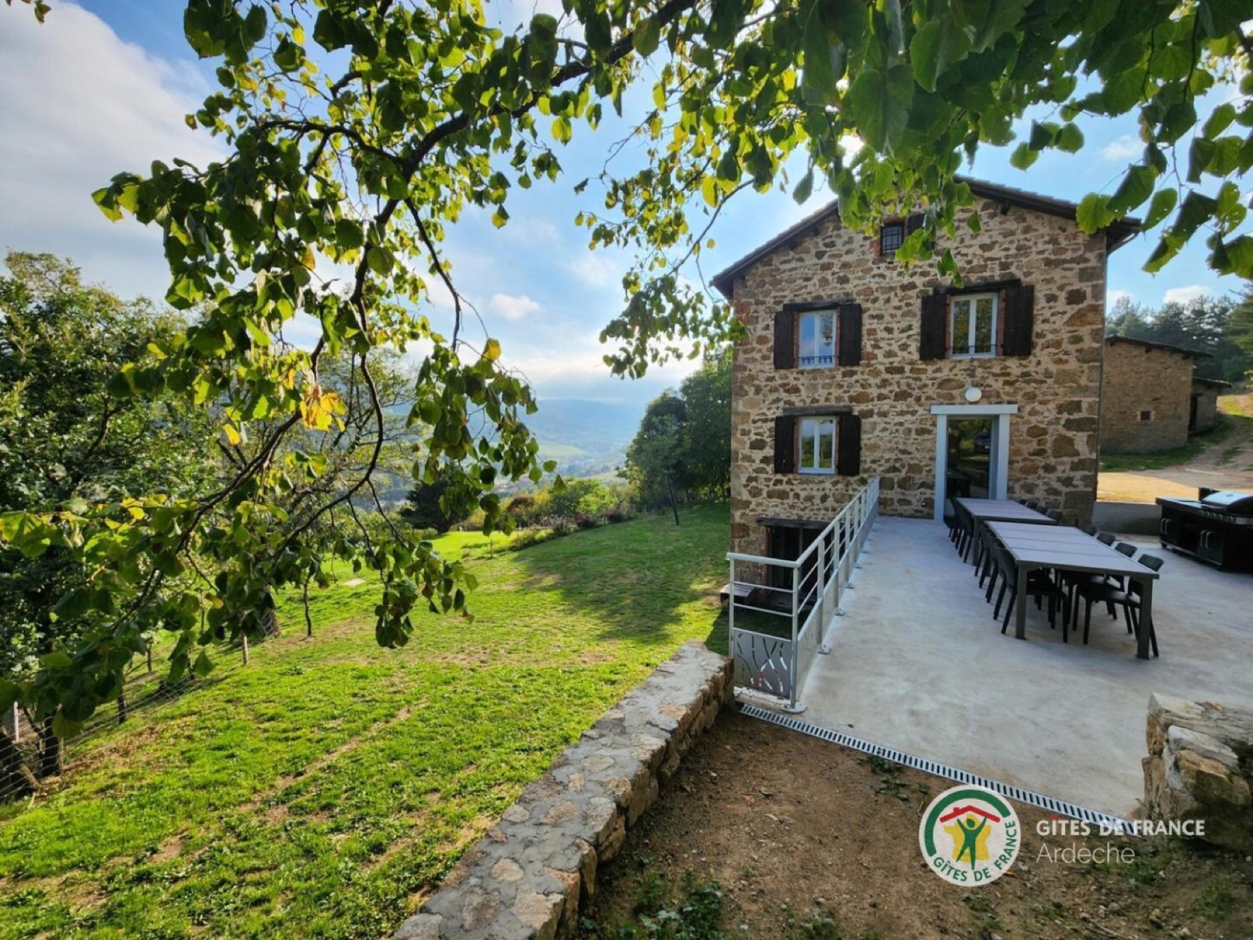 La Granja côté terrasse : la façade en pierre et la grande tablée dressée sous l'arbre