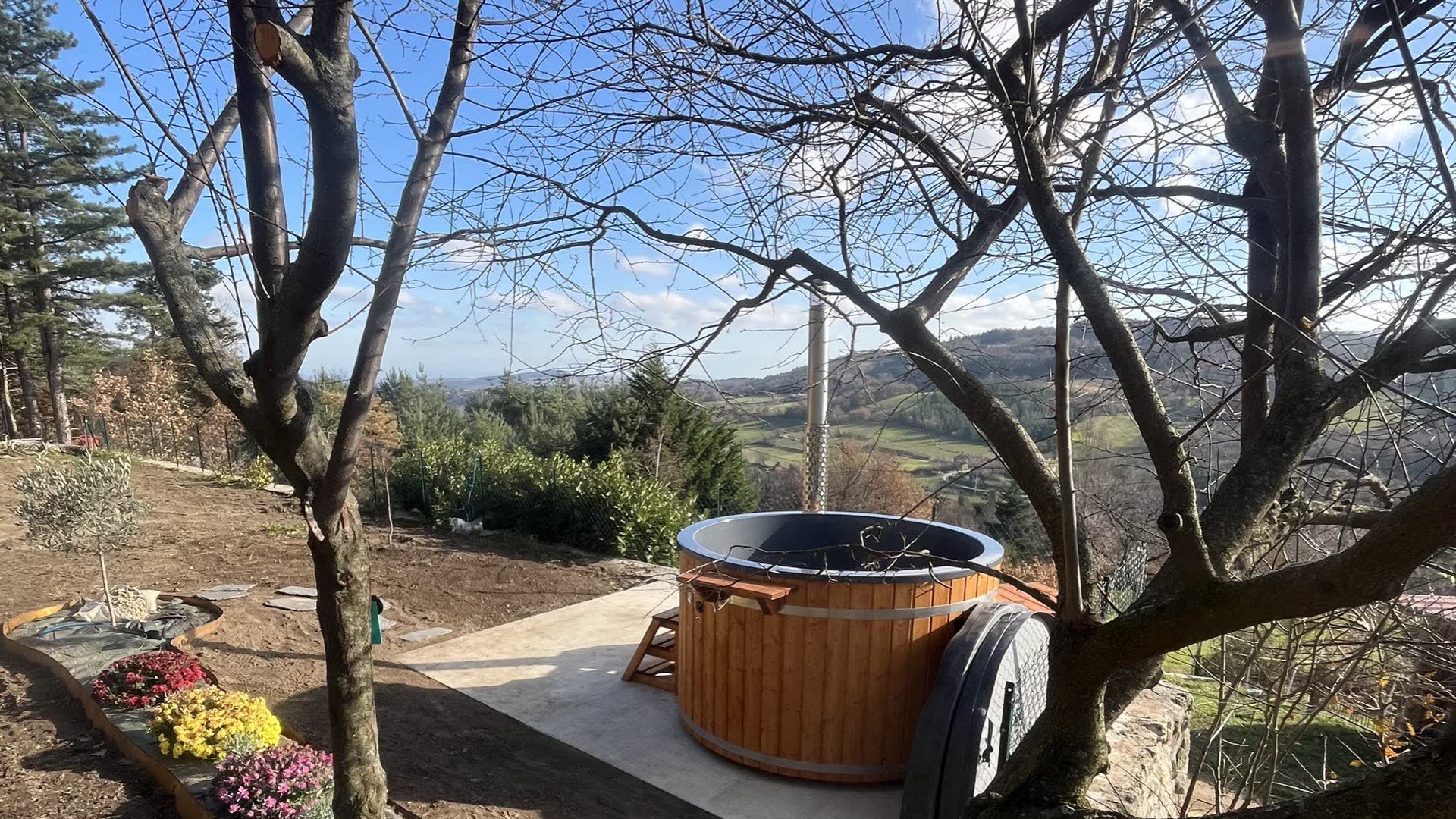 Bain nordique en bois du Domaine Solio posé sur sa terrasse, face aux collines de l'Ardèche verte
